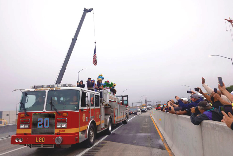 A photo of a fire truck with Philadelphia sports mascots riding on top on the newly opened temporary stretch of I-95