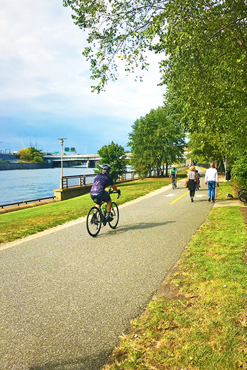 Bicyclists and walkers use a path that runs alongside of a river