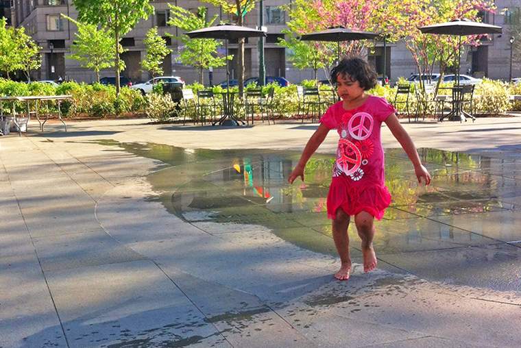 Young girl playing in fountain