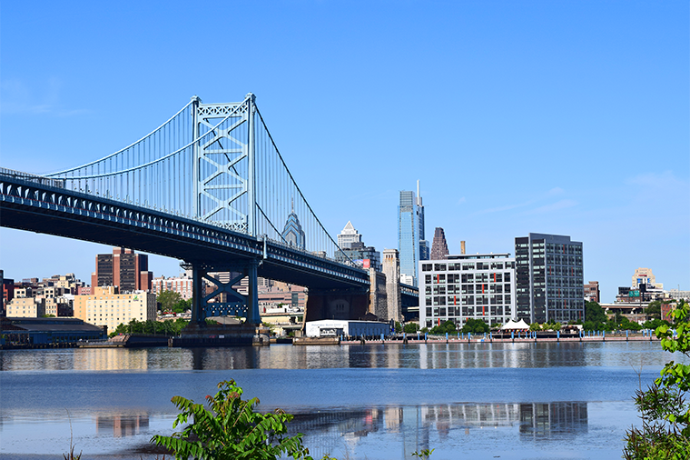 A photo of the Ben Franklin Bridge taken from the Camden Waterfront and showing Philadelphia in the distance