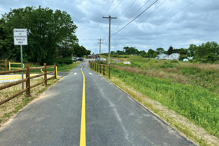 A photo of a two way multiuse path along a meadow