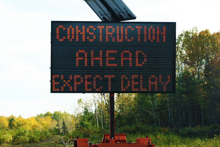 An electronic road sign that says "Construction Ahead. Expect Delay"