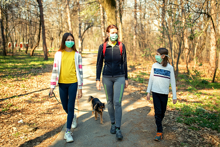 Family walking on a trail wearing face coverings