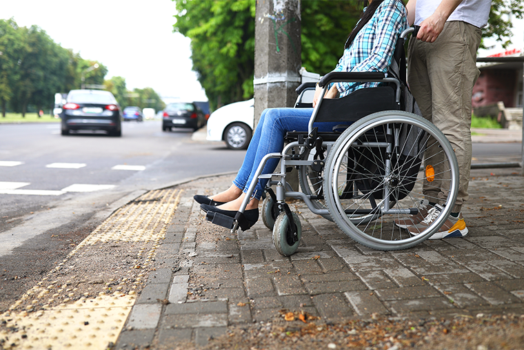 Person in wheelchair waiting to cross the street